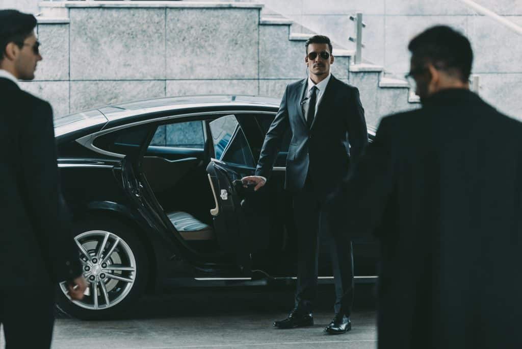 Agent de protection rapprochée ouvrant la portière de la voiture à son client