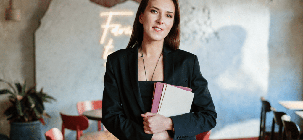 Femme d'affaires avec des dossiers dans un café moderne, souriante